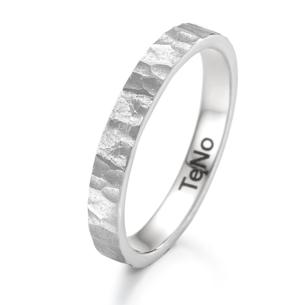 Beisteckring Der TeNo Beisteckring aus Edelstahl besticht durch seine markante, gehämmerte Oberfläche, die dem Ring einen zeitlosen und robusten Look verleiht. TeNo steht für moderne Eleganz und präzise Handwerkskunst, und dieser Ring ist ein perfektes Beispiel dafür. Das Design ist minimalistisch, aber dennoch ausdrucksstark, sodass der Ring vielseitig kombiniert werden kann %u2013 ob als dezentes Einzelstück oder in Kombination mit anderen Ringen. Die hochwertige Edelstahllegierung sorgt für eine hohe Widerstandsfähigkeit und Langlebigkeit, was diesen Ring zu einem perfekten täglichen Begleiter macht. Ein zeitloses Schmuckstück für Liebhaber klarer Formen und langlebiger Materialien. 069.1700.D86.XX